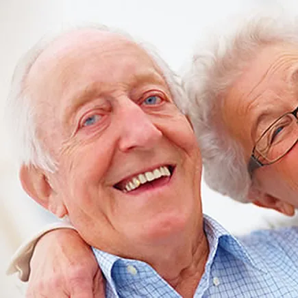 A senior couple laughing, with implant-supported smiles