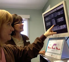 A hygienist reviewing digital x-rays with a patient on screen